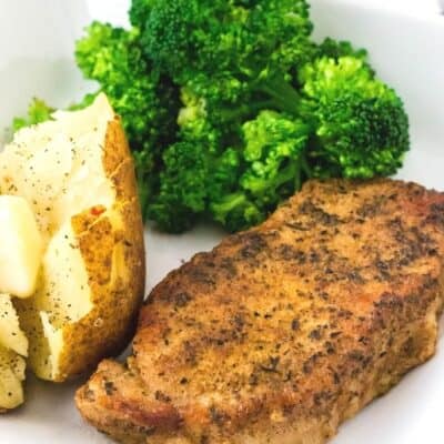 Instant Pot pork chop served on a white plate with baked potato and broccoli
