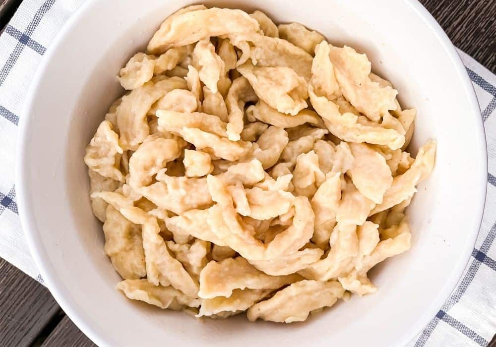 spaetzles in a white bowl for serving, resting atop a blue and white checkered napkin