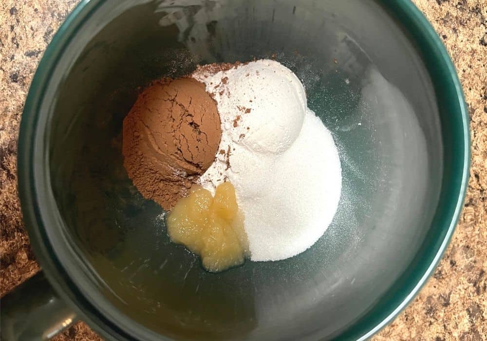 flour, sugar, cocoa powder, and applesauce in a mug.