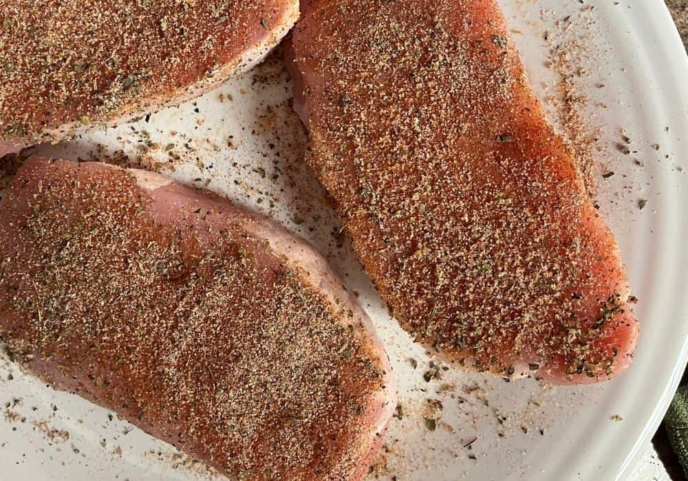raw boneless pork chops with seasonings rubbed into them prior to cooking in the Instant Pot