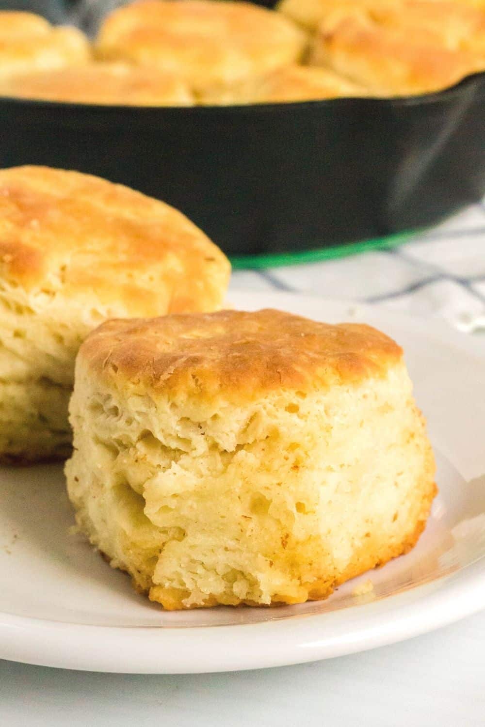 close-up side view of a homemade sour cream biscuit on a white plate