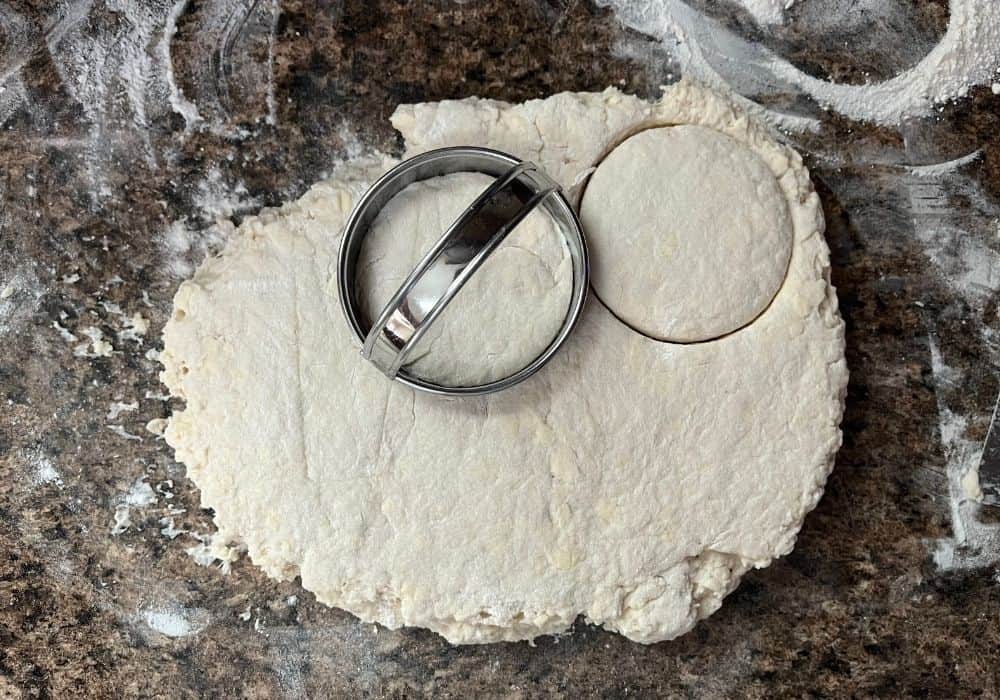 a biscuit cutter cuts rounds of dough