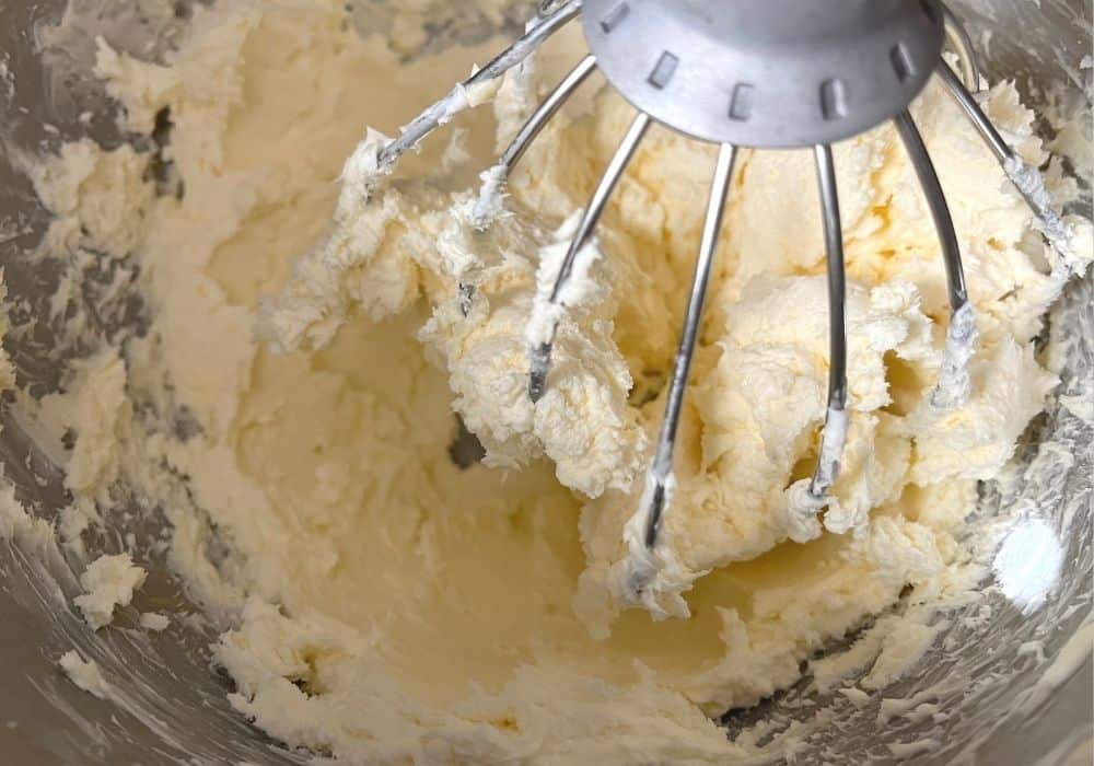 butter and cream cheese mixed together in the bowl of a stand mixer