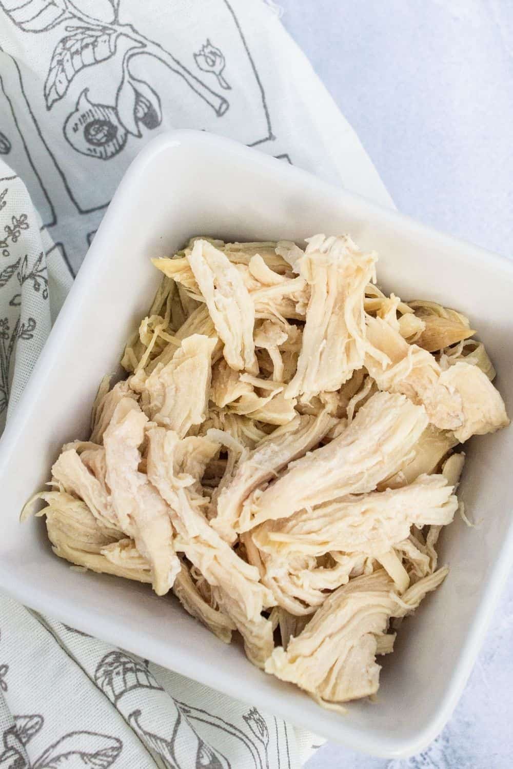 shredded chicken in a white square bowl, which was cooked from frozen in the pressure cooker