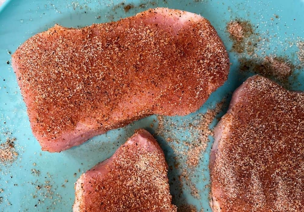 raw boneless pork chops with seasonings rubbed in, prior to cooking in the pressure cooker