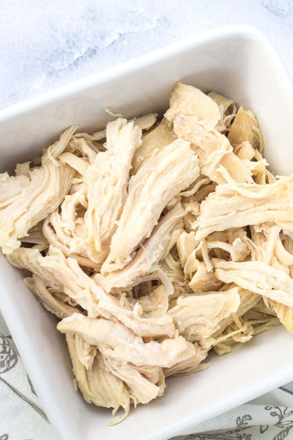 white bowl of pulled chicken that was cooked from frozen in the instant pot