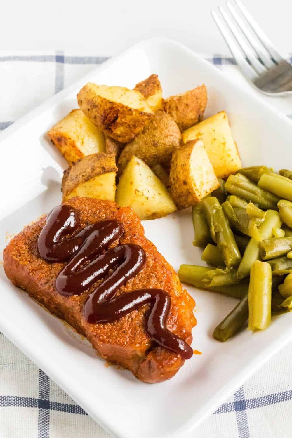 pressure cooker pork chop with bbq sauce, with side dishes of roasted potatoes and green beans
