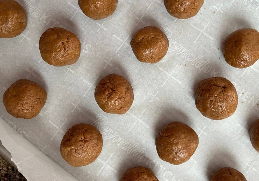 biscoff cookie balls on a parchment-lined baking sheet, ready to be chilled in refrigerator.