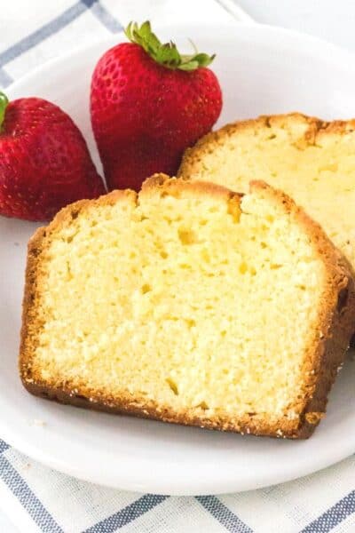 two slices of cream cheese pound cake on a white plate with strawberries