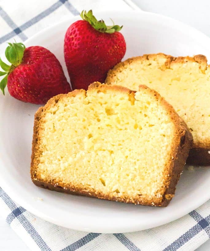 two slices of cream cheese pound cake on a white plate with strawberries