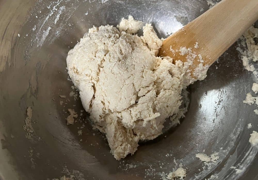 shaggy dumpling dough mixed together in a mixing bowl with a wooden spoon.