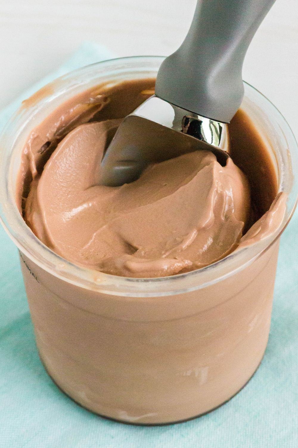 smooth and creamy chocolate Ninja Creami ice cream in a pint, with an ice cream scoop in it.