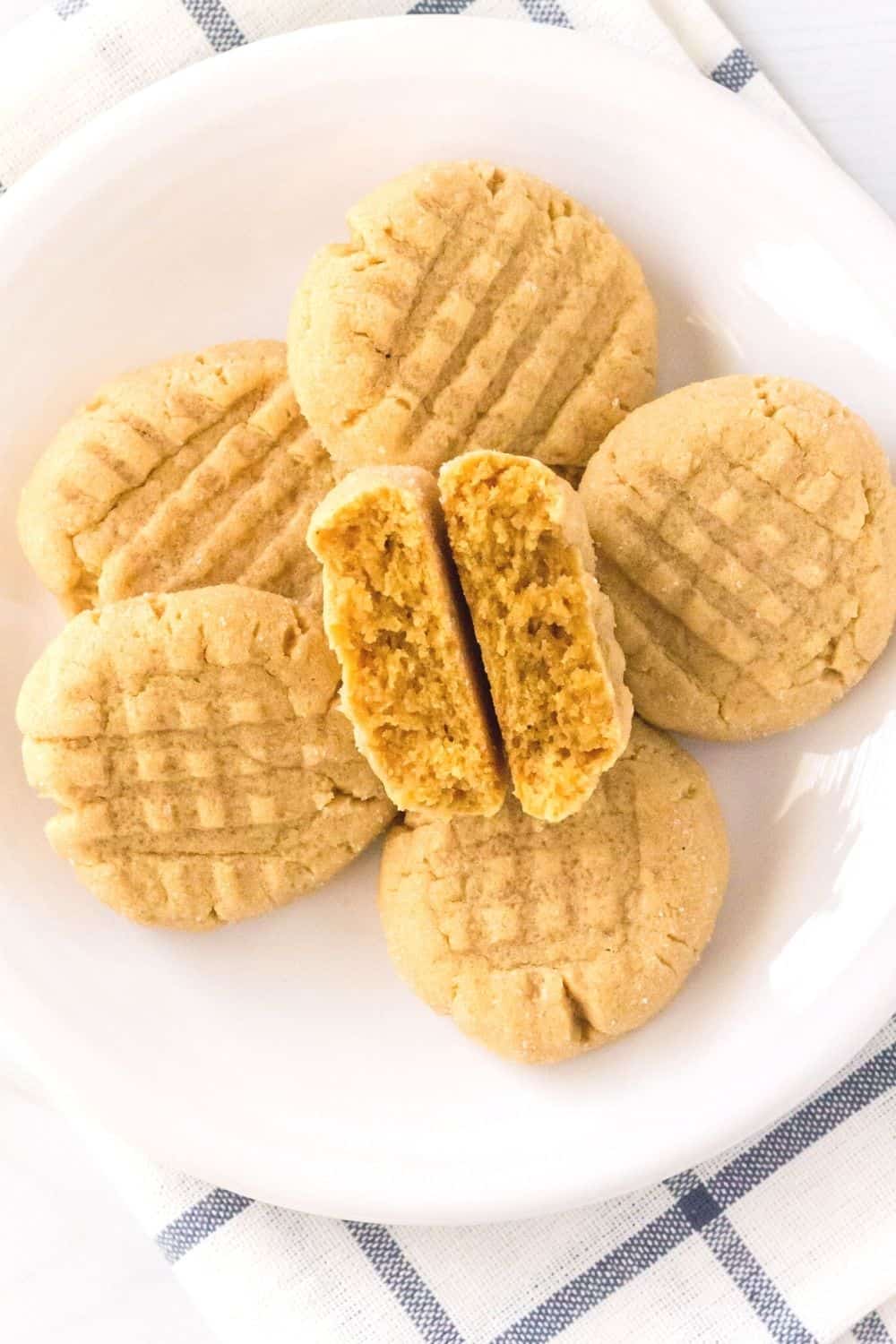 overhead view of a plate of cake mix peanut butter cookies, with one cookie broken in half to show the soft interior