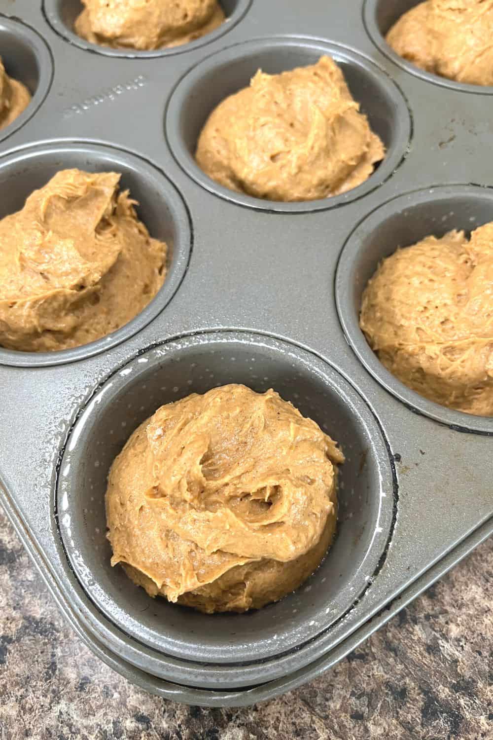 cake mix pumpkin muffin batter in a greased muffin pan, ready for baking