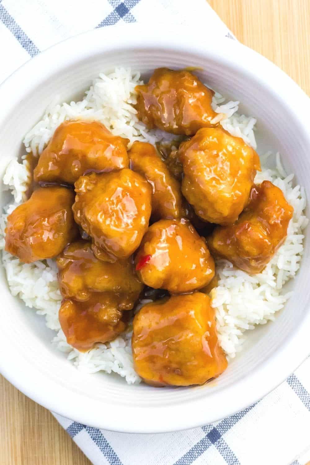 overhead view of a white bowl with a serving of white rice and air fryer orange chicken
