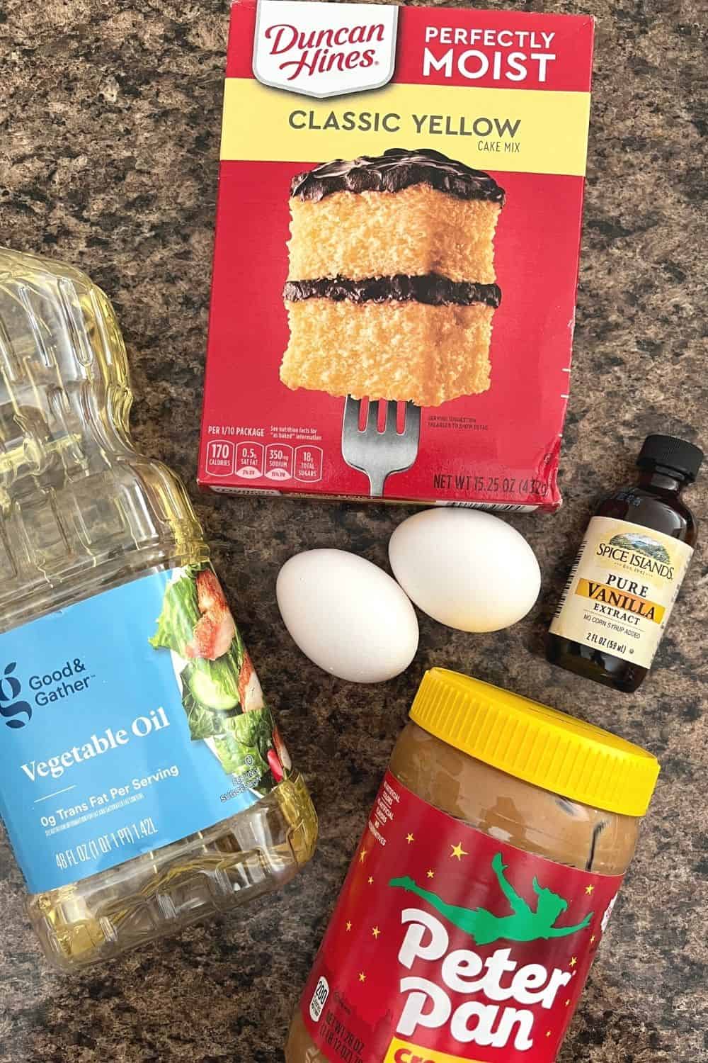 Ingredients for cake mix peanut butter cookies, including a box of yellow cake mix, vegetable oil, eggs, vanilla extract, and creamy peanut butter