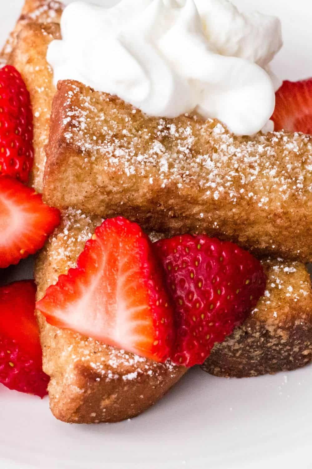 close-up view of strawberries, french toast sticks, and whipped cream