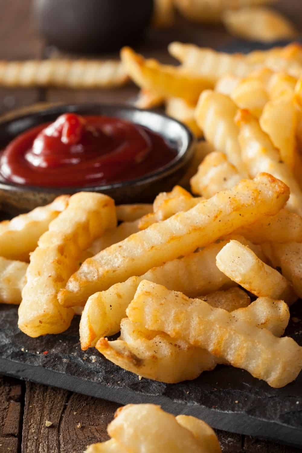 close-up view of freshly baked air fryer frozen crinkle french fries with a serving of ketchup