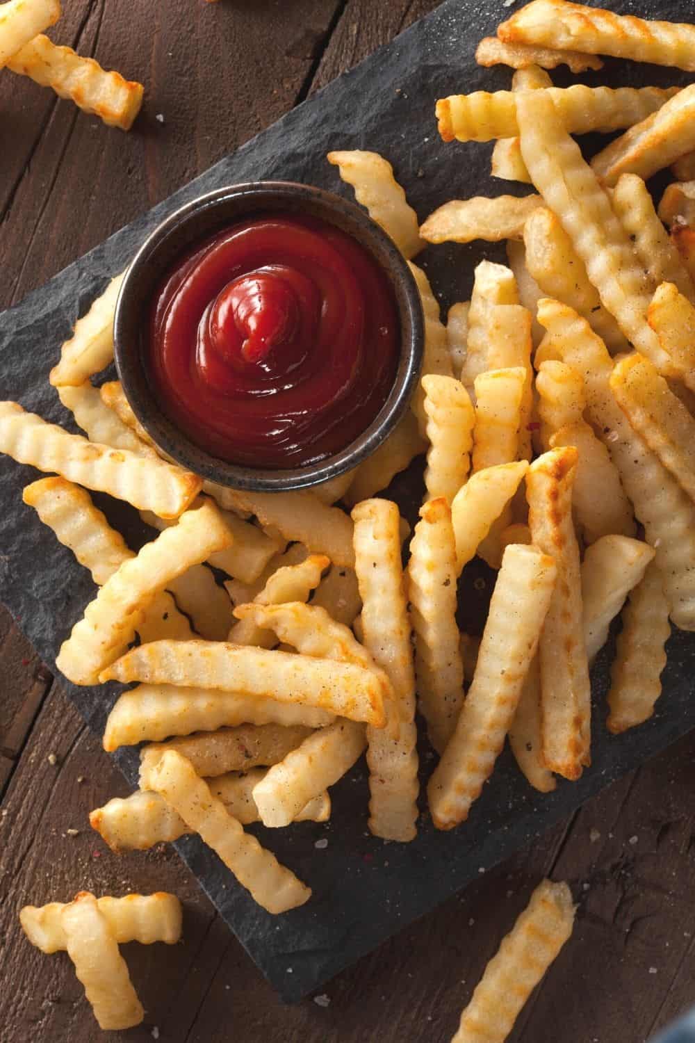 overhead view of a pile of frozen crinkle fries baked in the air fryer and served with ketchup
