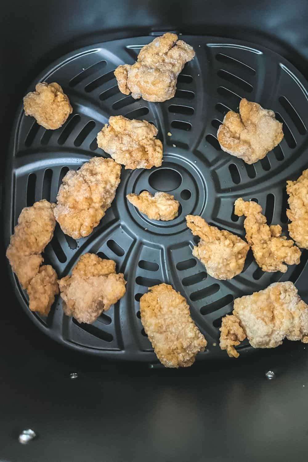 frozen chicken nuggets in the air fryer basket, ready to be cooked