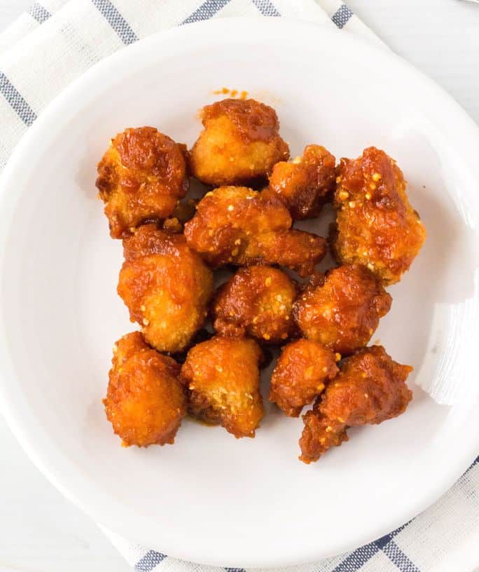 air fryer frozen cauliflower wings tossed in sauce and served on a white plate