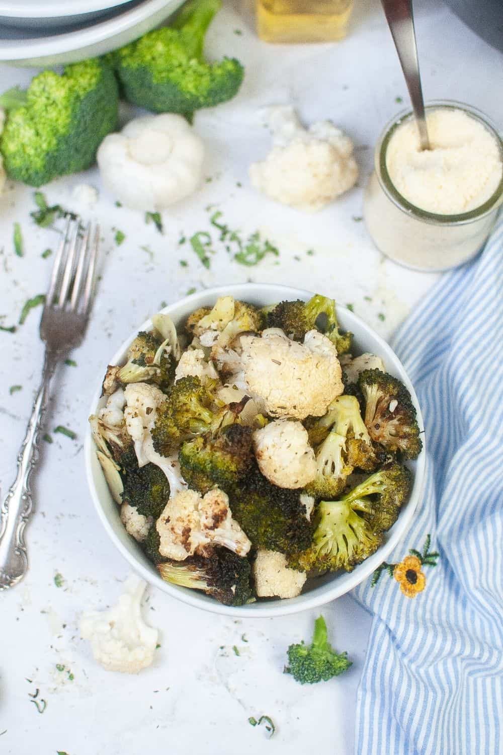 overhead view of broccoli and cauliflower roasted in the air fryer, served in a white bowl