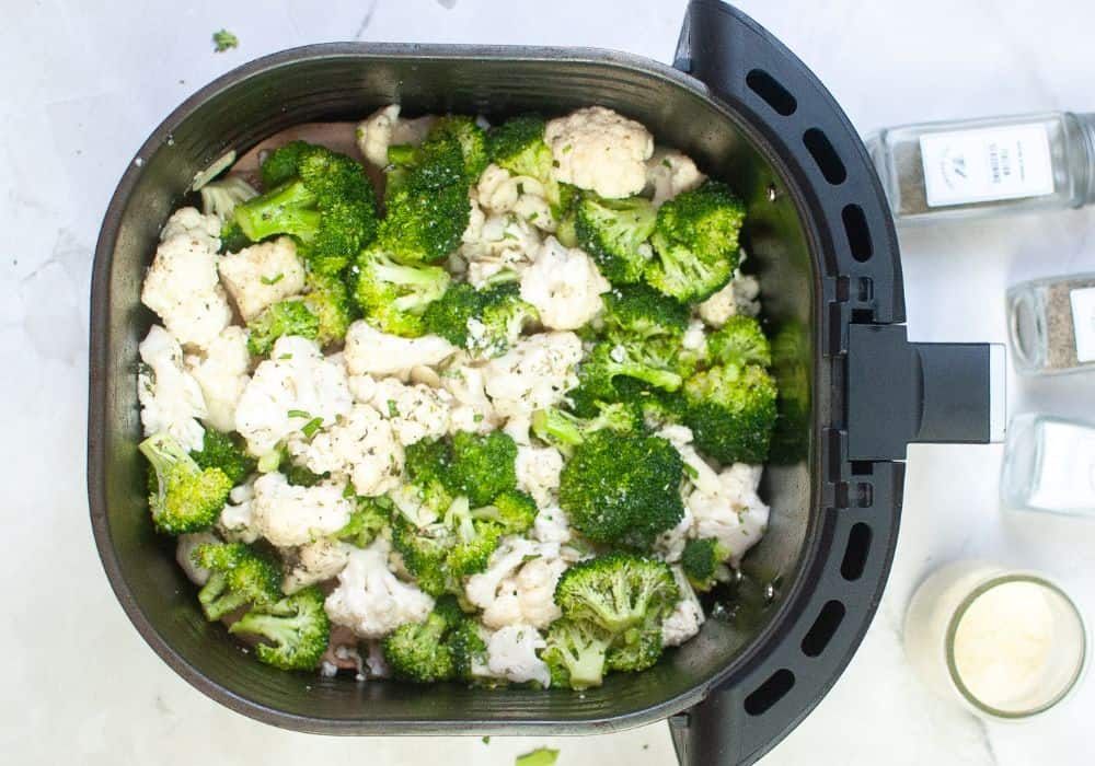 seasoned broccoli and cauliflower in an air fryer basket