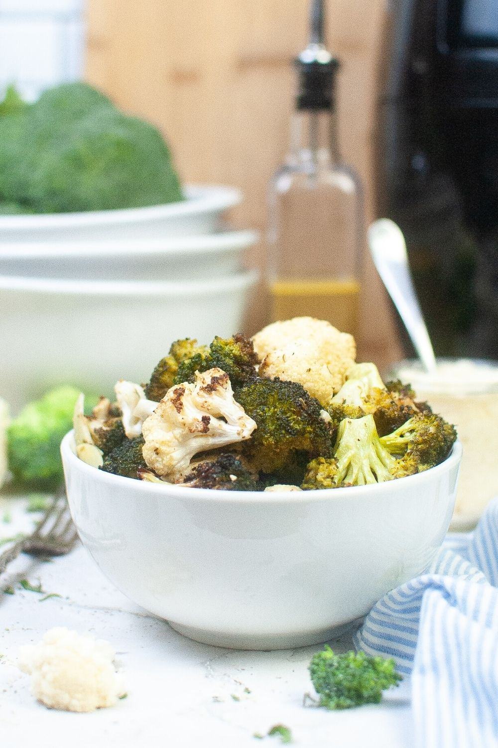 side view of a white bowl with air fried broccoli and cauliflower served in it