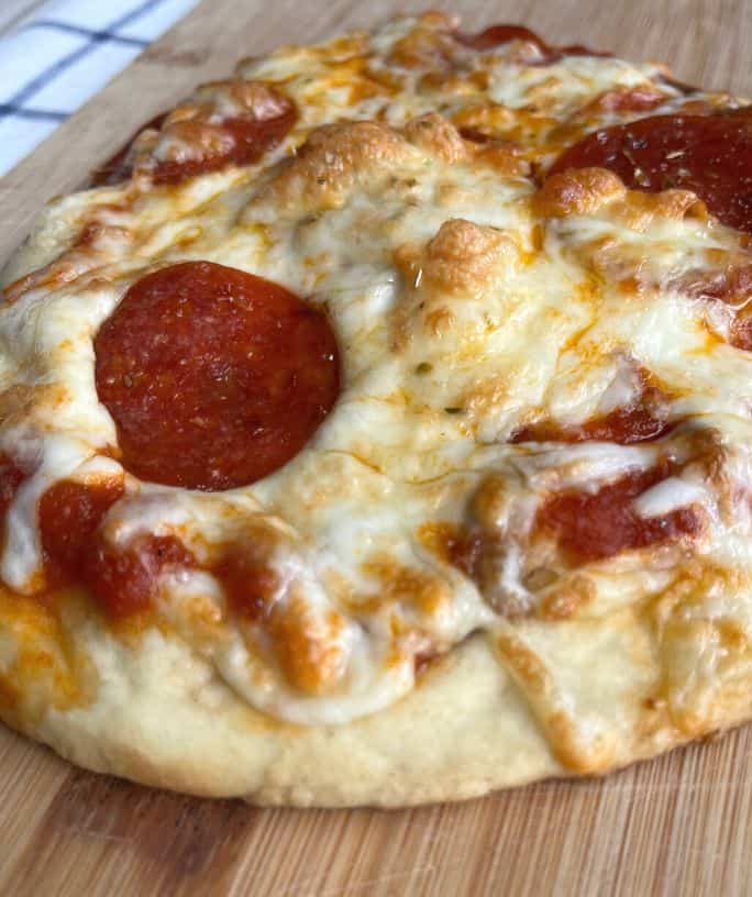 air fryer naan pizza with pepperoni on a wooden cutting board