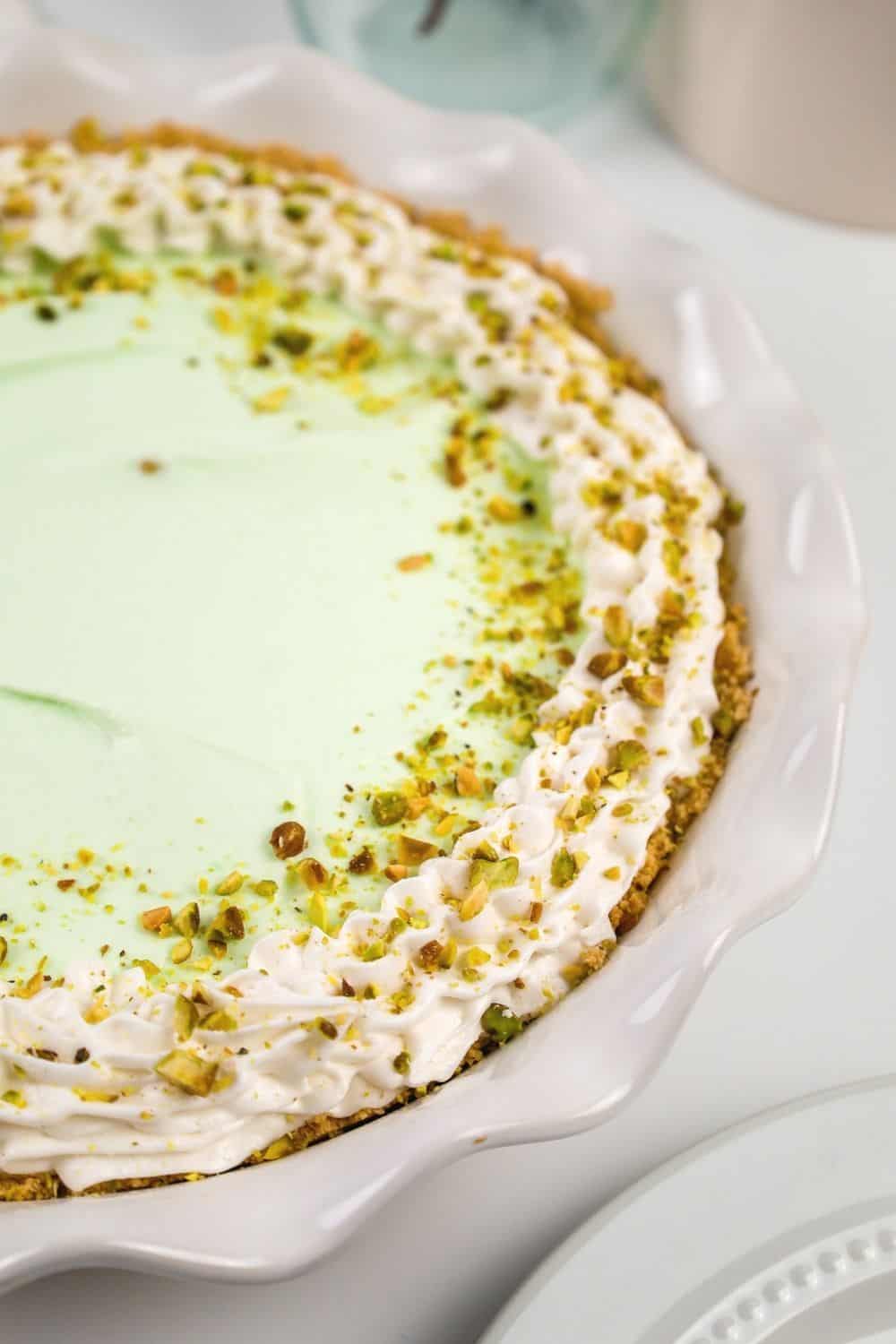 close-up view of the edge of the pie, with whipped cream piped around the edge and finely chopped pistachios sprinkled as a garnish