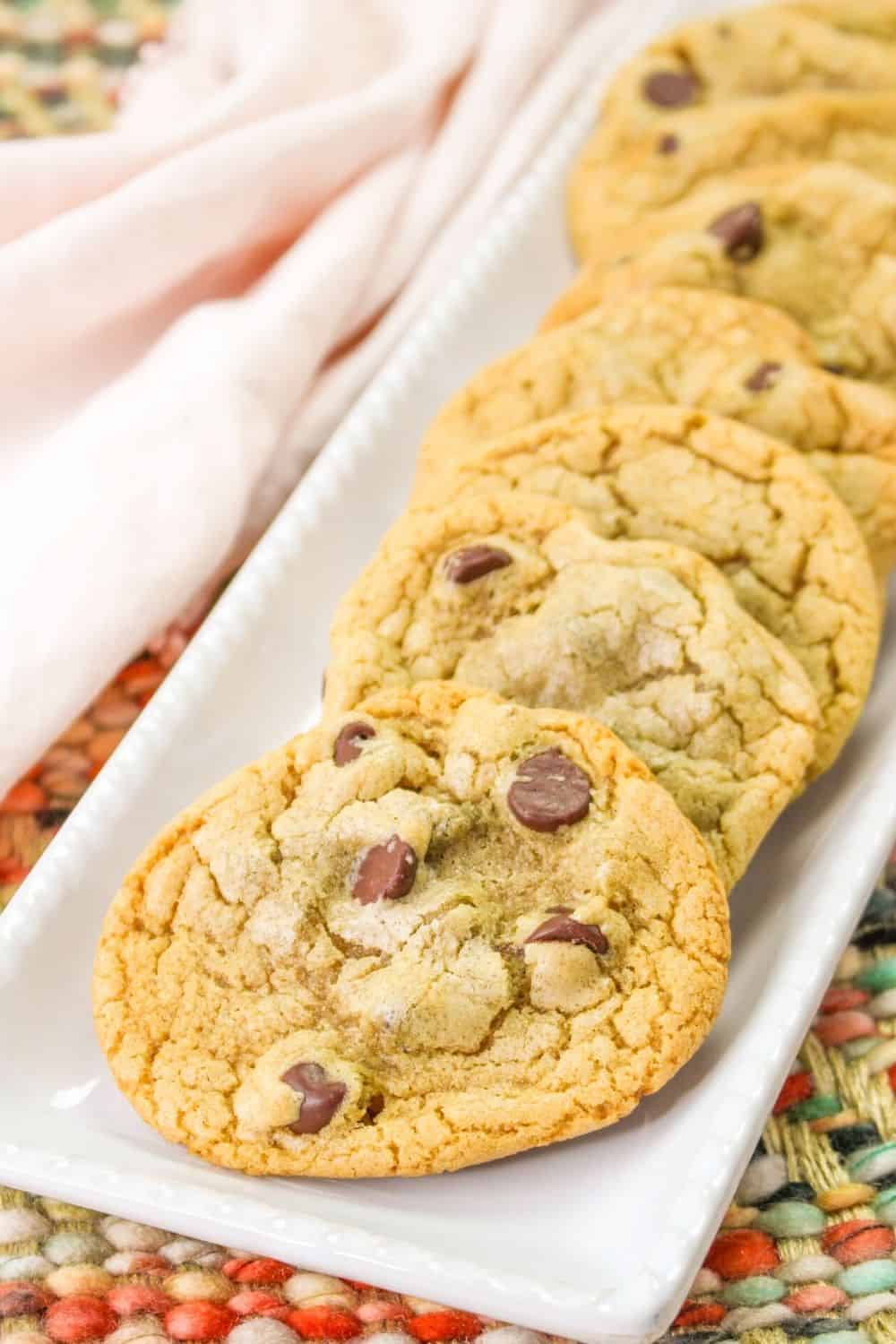 several chocolate chip cookies made with vegetable oil are served on a white platter