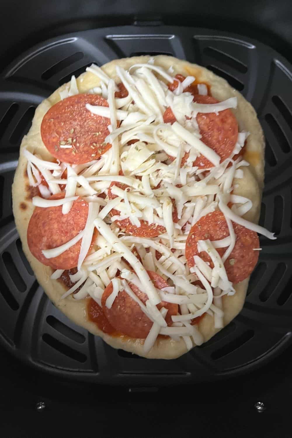 unbaked naan pizza in the basket of an air fryer