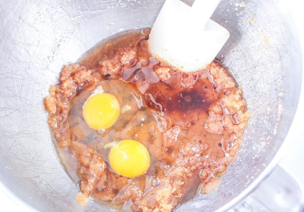 two eggs added to the sugar and oil mixture in the mixing bowl