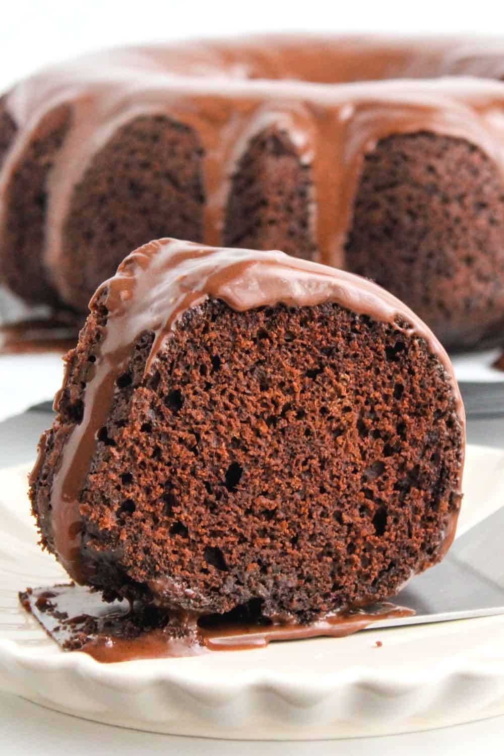 close-up view of a slice of chocolate fudge cake, with the remaining bundt cake in the background