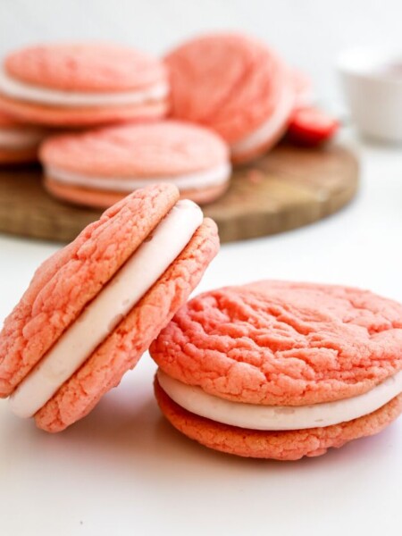 two strawberry sandwich cookies in the foreground, with more whoopie pies in the background