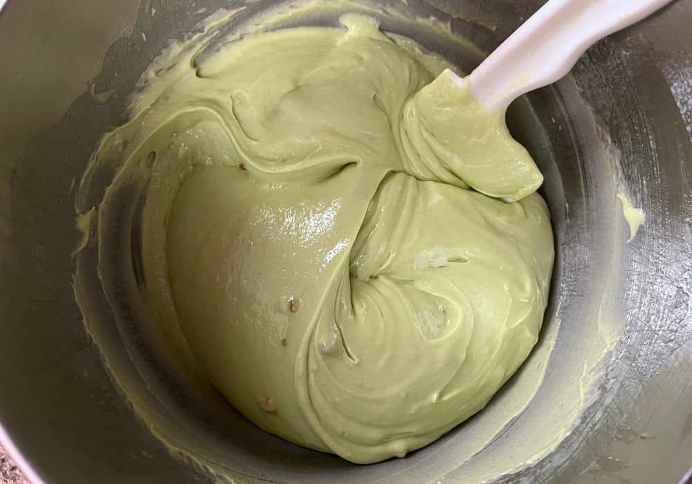 cake batter for pistachio cake, aka watergate cake, in a bowl with a spatula in it