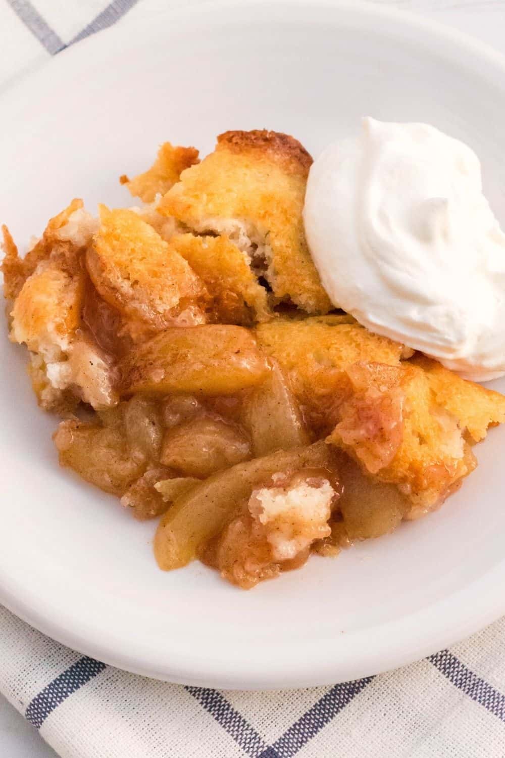close-up overhead view of spiced pear cobbler, made with fresh pears, on a white plate served with whipped cream.