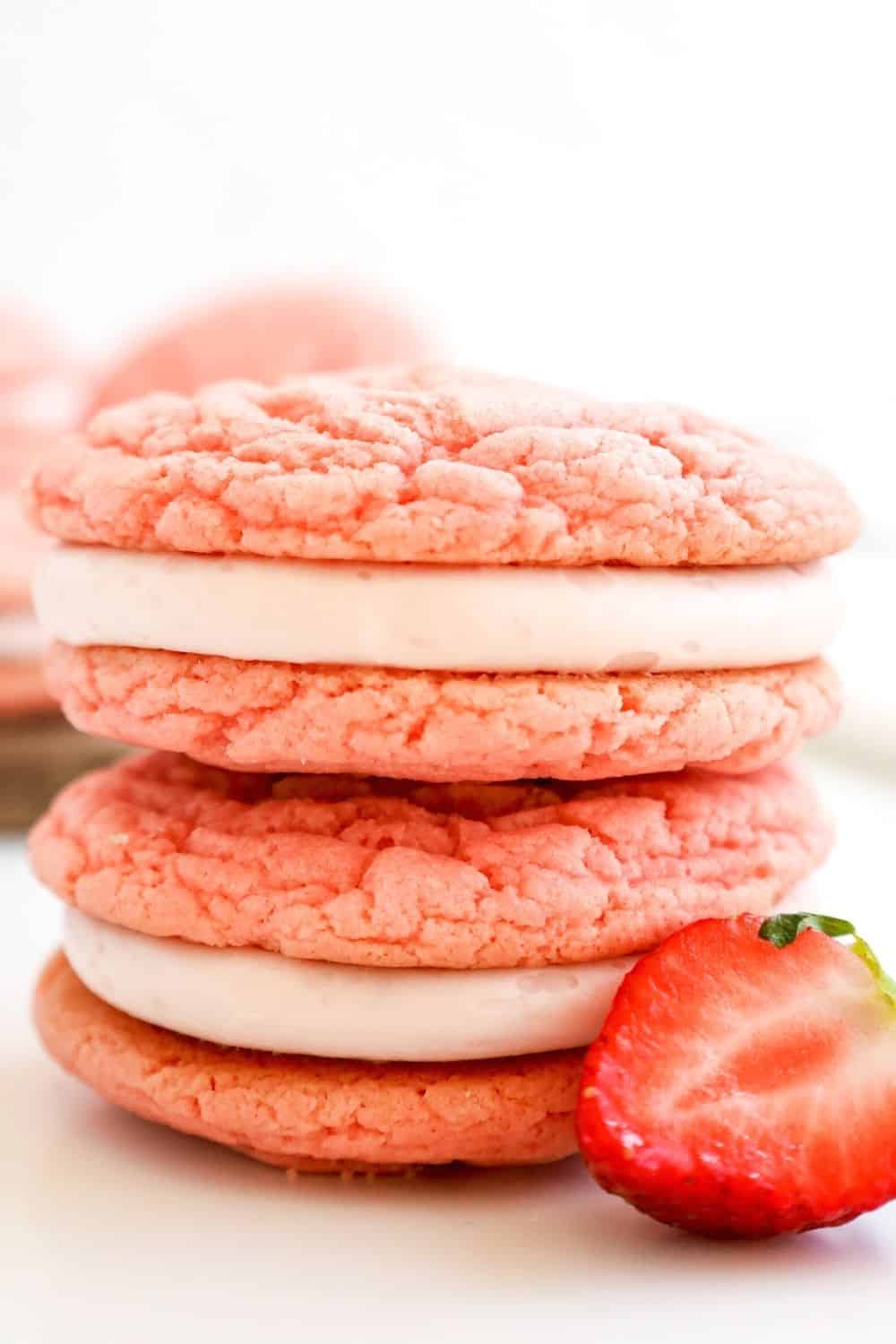 two strawberry whoopie pies stacked together with a fresh strawberry next to it