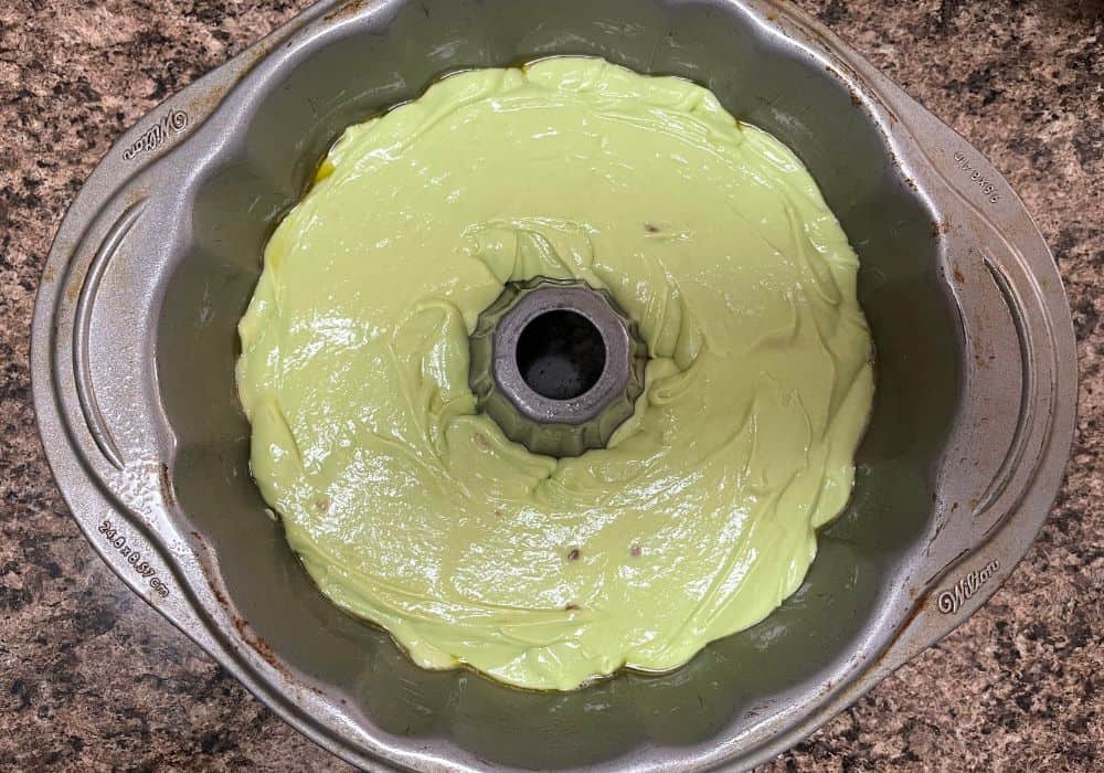 pistachio pudding cake batter poured into a greased bundt pan, ready to be baked