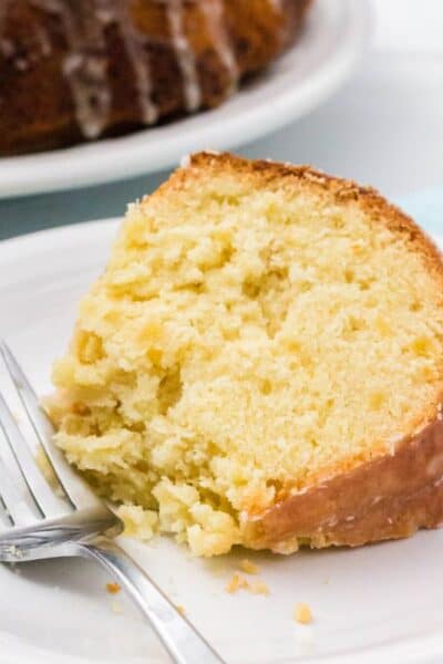 close-up view of a slice of pineapple pound cake, with a bite taken out of it, on a white plate