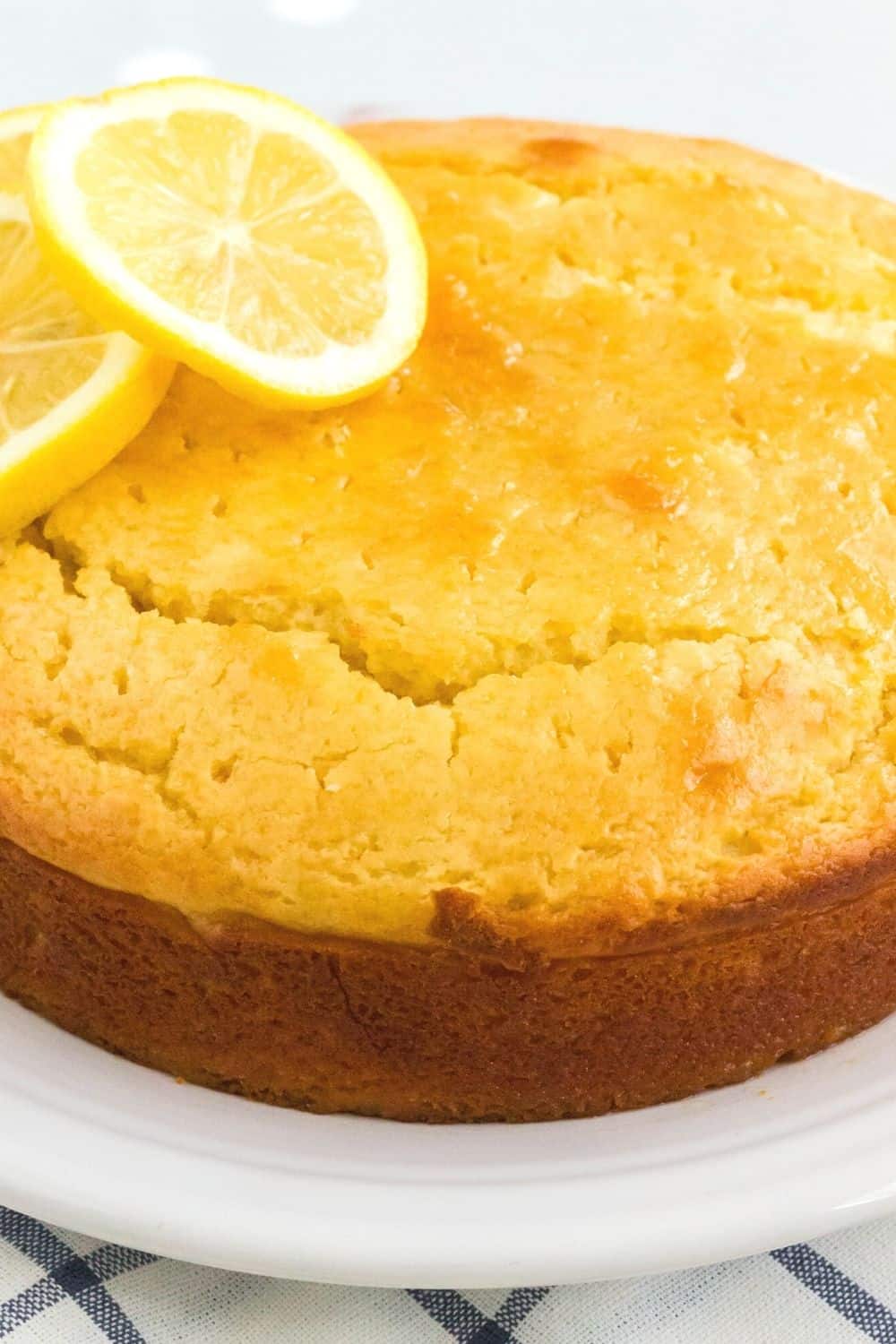 side view of a lemon syrup cake, showing the golden-brown edges and the syrup drizzled in through small holes.
