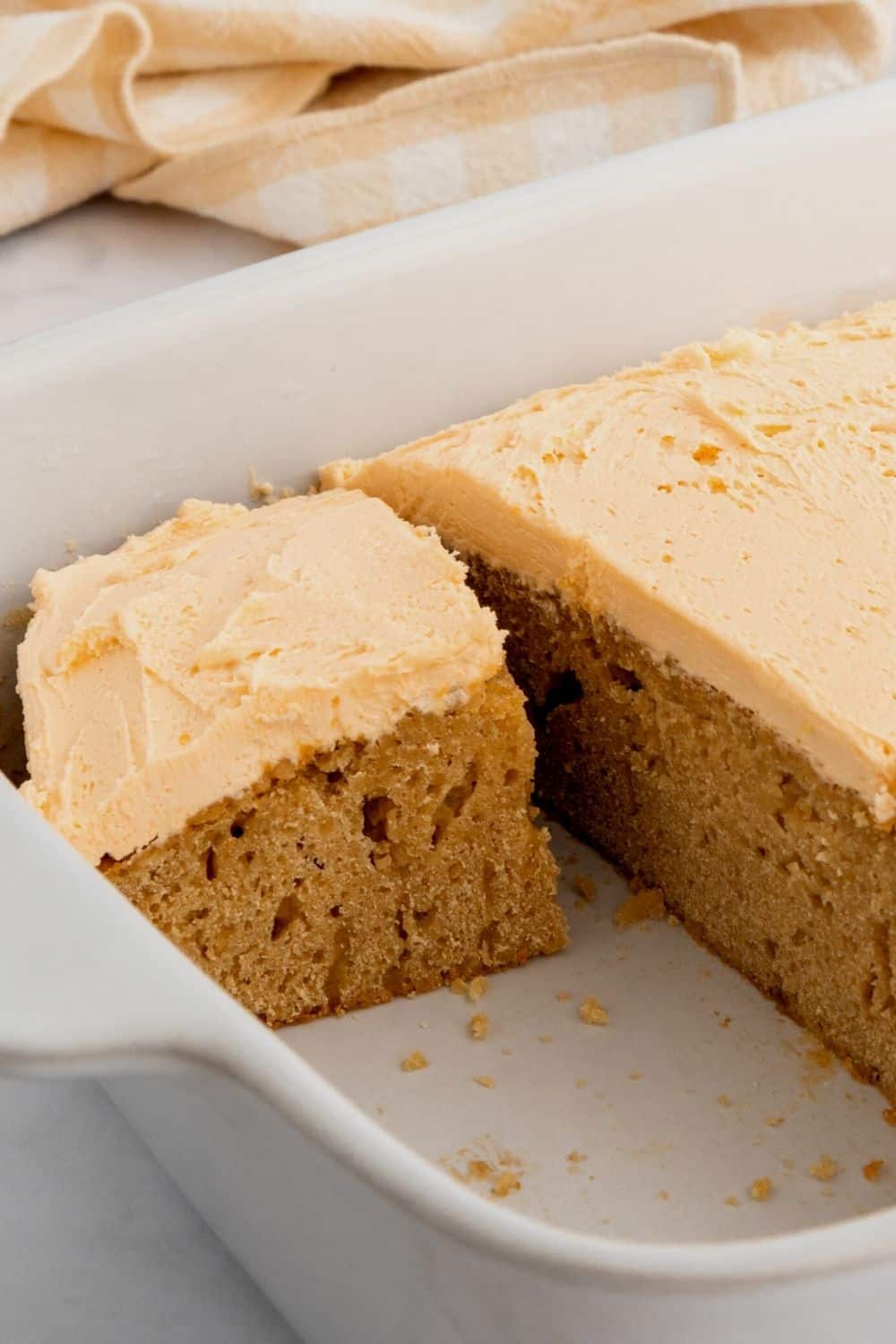 close-up view of a slice of homemade butterscotch cake, topped with butterscotch frosting, cut from the pan.