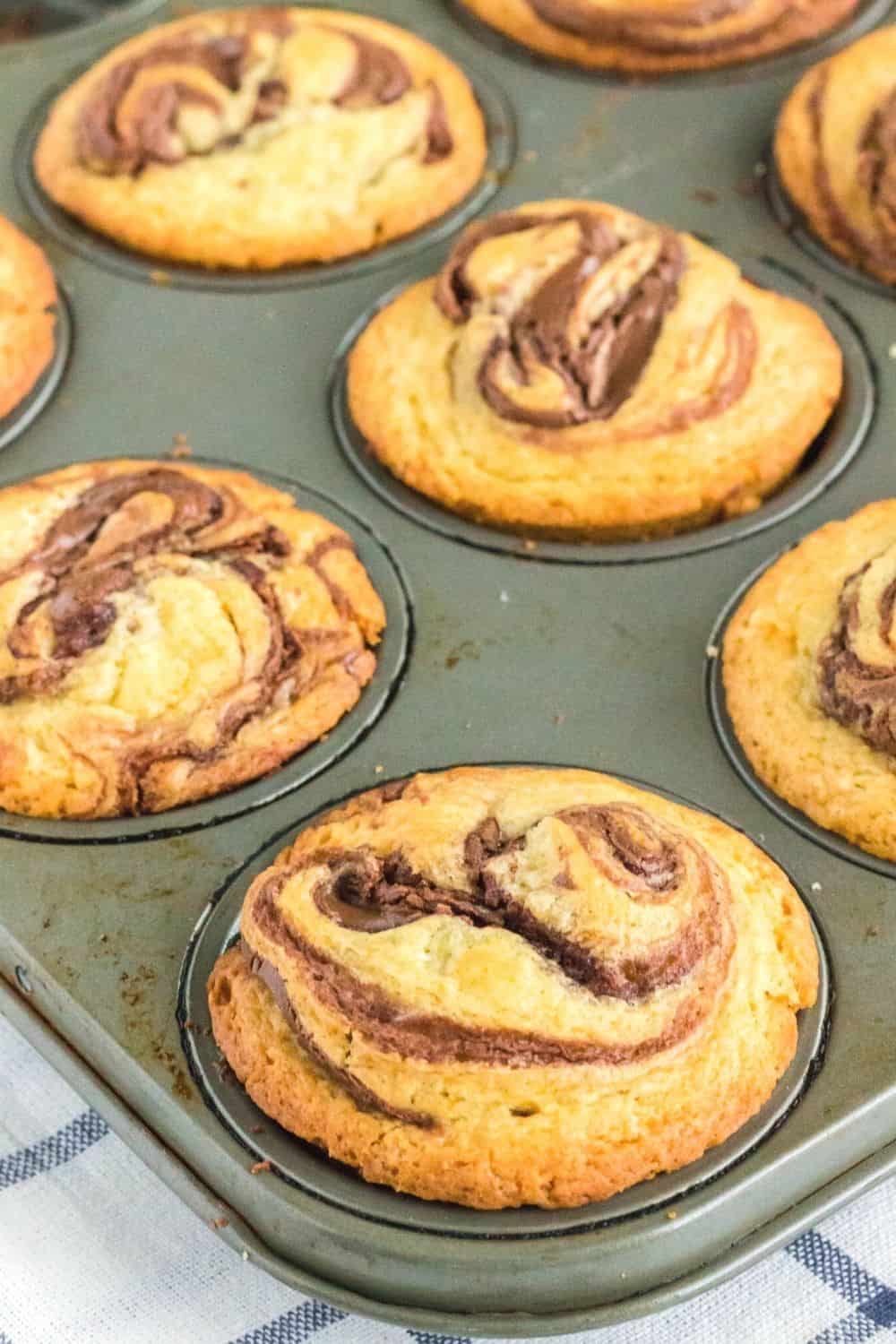 golden brown muffins with chocolate hazelnut spread are in a muffin tin, fresh out of the oven.
