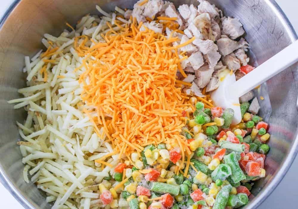hash browns, cheese, frozen veggies, and diced chicken added to the cream mixture in the mixing bowl.