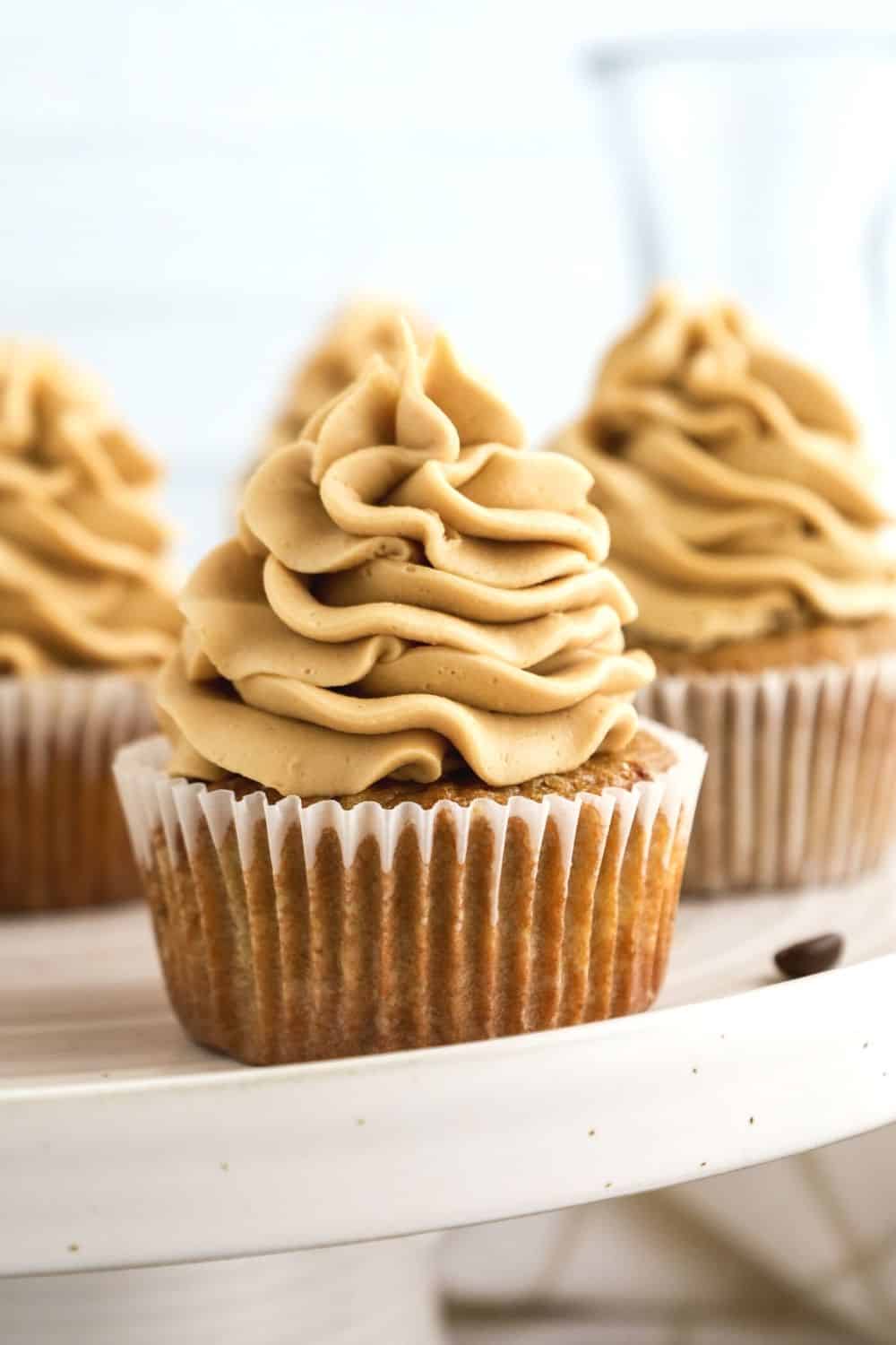 close-up side view of coffee cupcakes on a white cake stand
