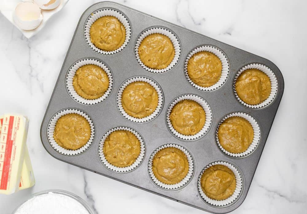cupcake batter added to lined muffin wells of a muffin pan
