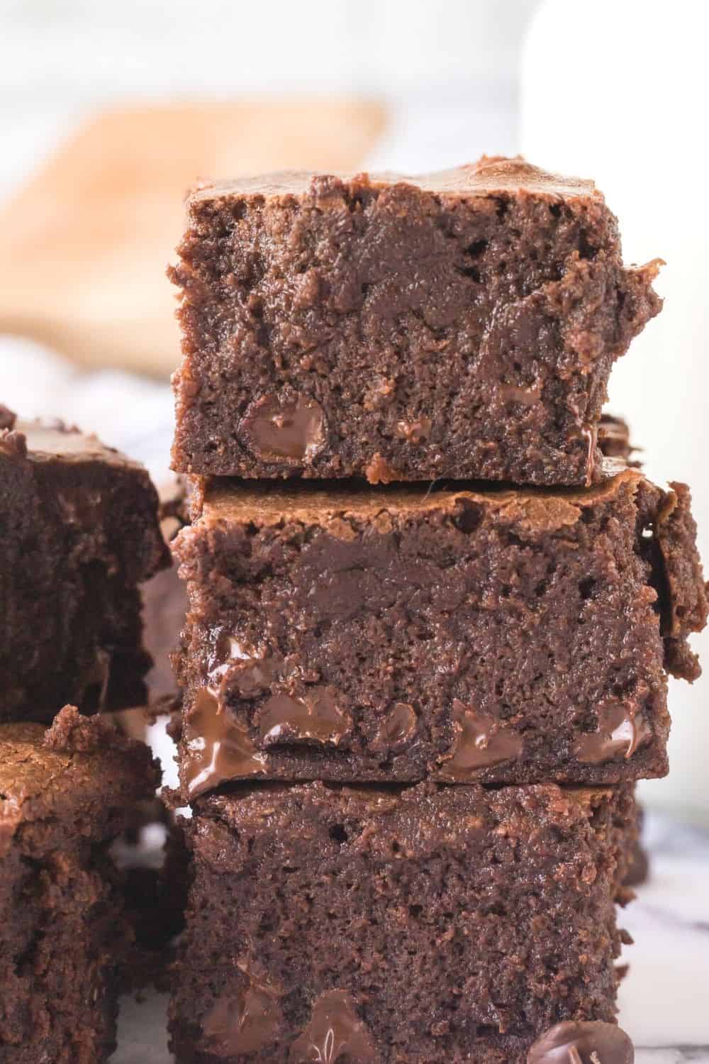 side view of three sweetened condensed milk brownies stacked on top of each other, showing the moist and fudgy texture.