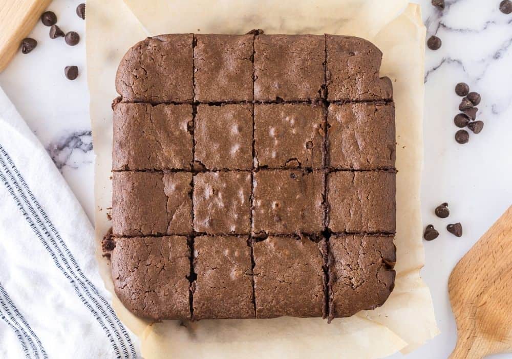 condensed milk brownies removed from the pan using parchment paper, then sliced into sixteen squares.
