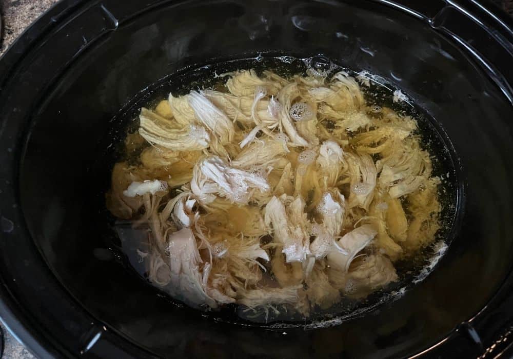 shredded chicken added to broth in a Crock Pot, for making chicken and dumplings.