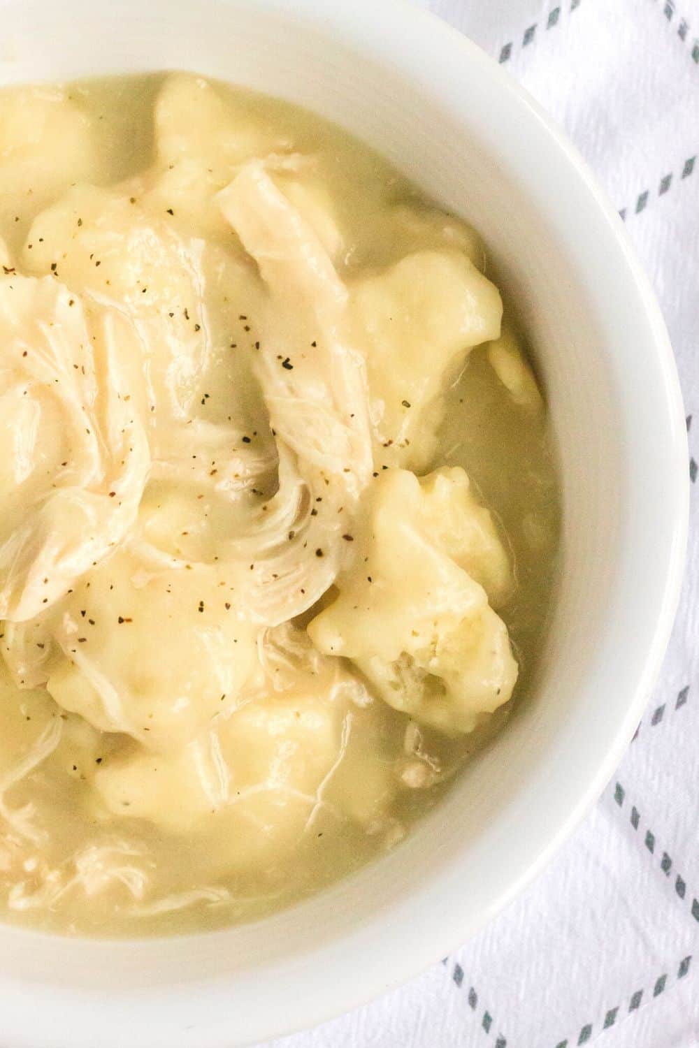 overhead view of a white bowl filled with homemade slow cooker chicken and dumplings